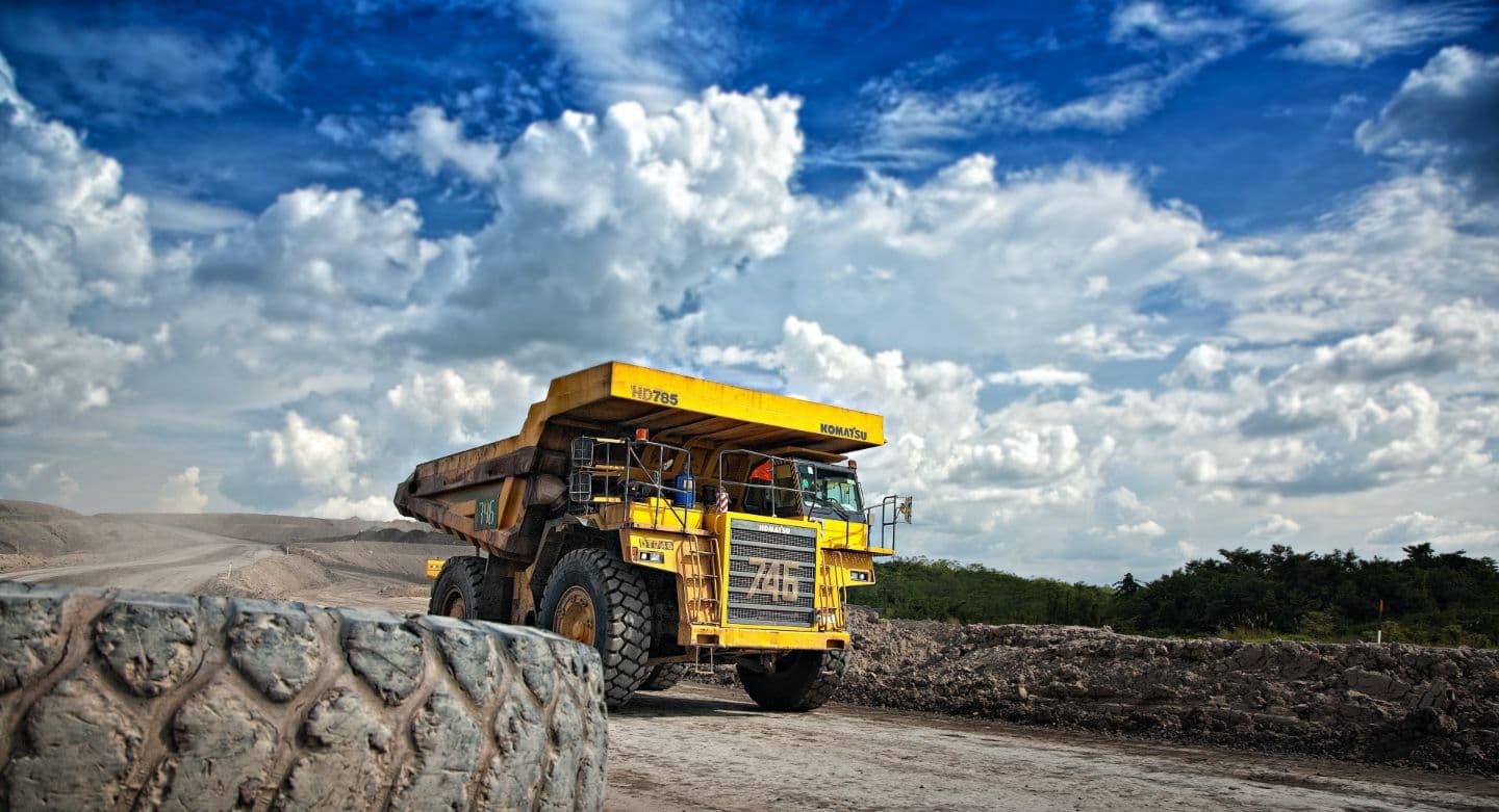 yellow mining dump tuck on path with wheel in foreground